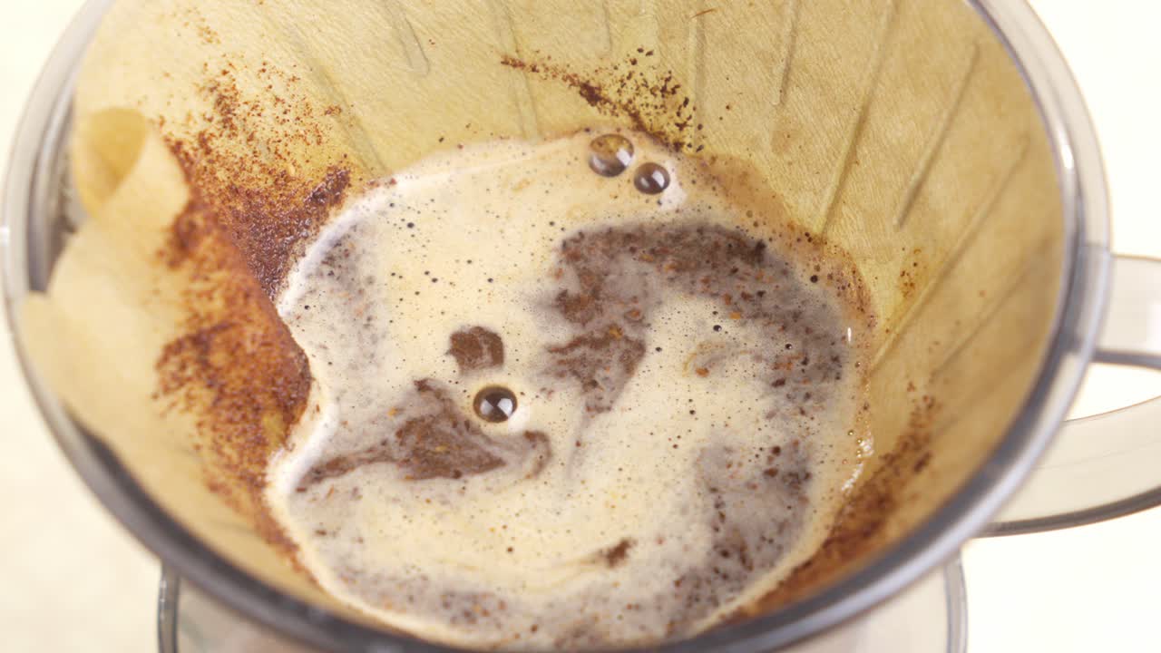 Water poured over coffee grounds in pour over filter starting fresh brew cycle, medium overview static