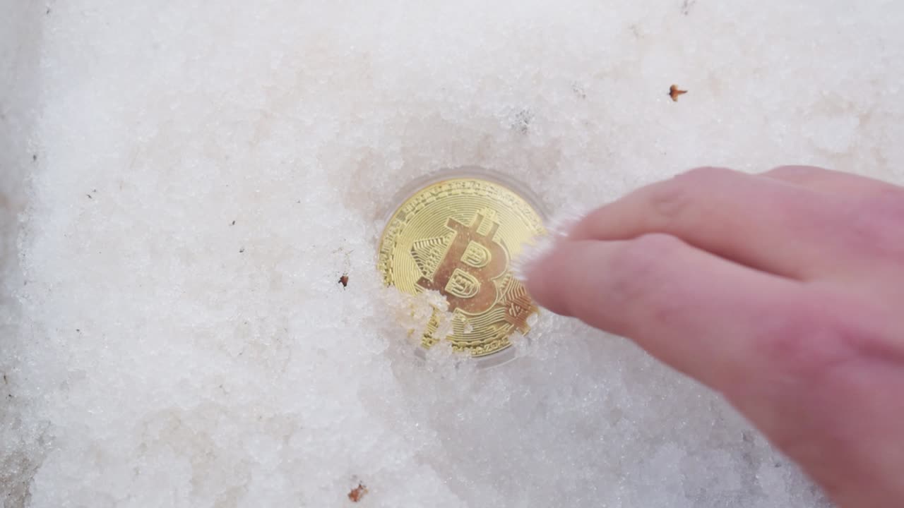 mano masculina excavando bitcoin dorado de la nieve-1