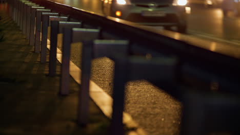 Night-city-highway-guardrail-established-at-sidewalk-along-highway-closeup.