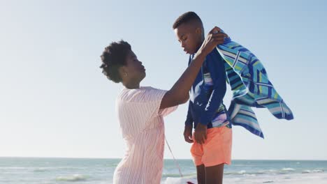 Video-De-Una-Feliz-Madre-Afroamericana-Cubriendo-A-Su-Hijo-En-La-Playa