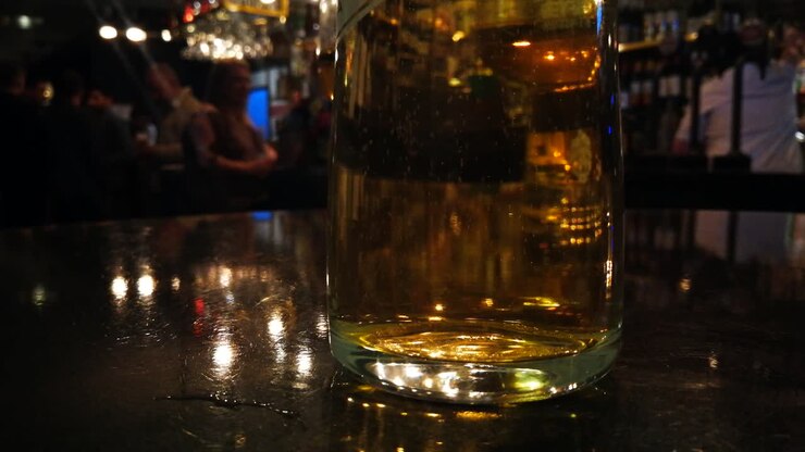 Filmato di bollicine che salgono in una bevanda, con uno sfondo sfocato di persone che si divertono in un bar.