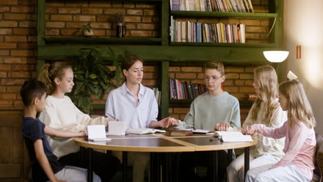 Teacher-and-kids-holding-hands-and-praying-on-class