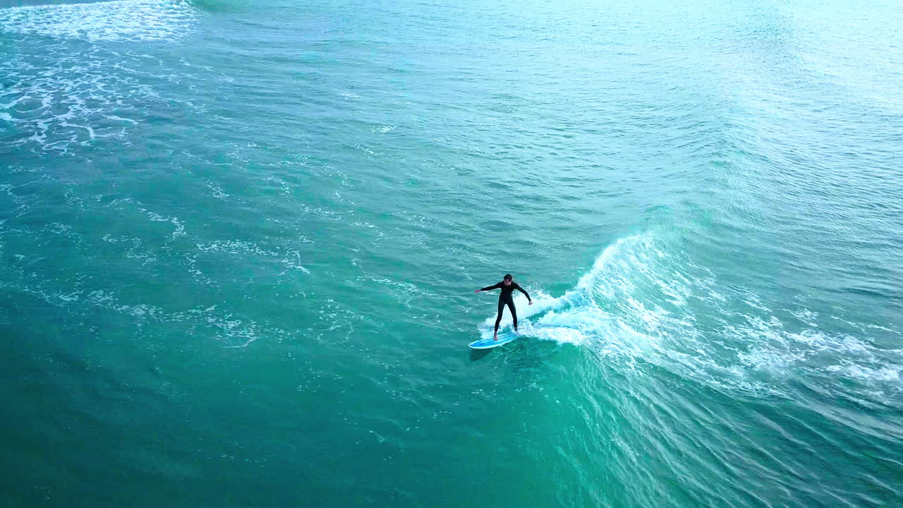 A surfer paddles and takes off on an Indian Ocean swell, drone