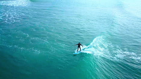 a surfer paddles and takes off on an indian ocean swell, drone