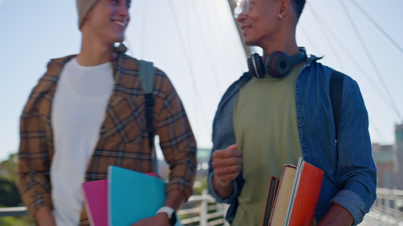 Two students walking together across a bridge