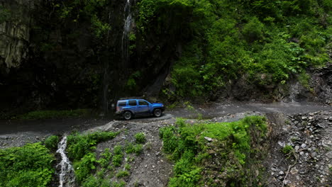 off-road vehicle driving on abano pass passing by on waterfall in georgia