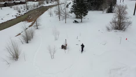 vista aérea de una mujer solitaria con raquetas de nieve caminando sobre la nieve en la ruta de senderismo de invierno junto al río cerca de ouray, suroeste de colorado, ee.uu., tiro de drone inclinado hacia arriba