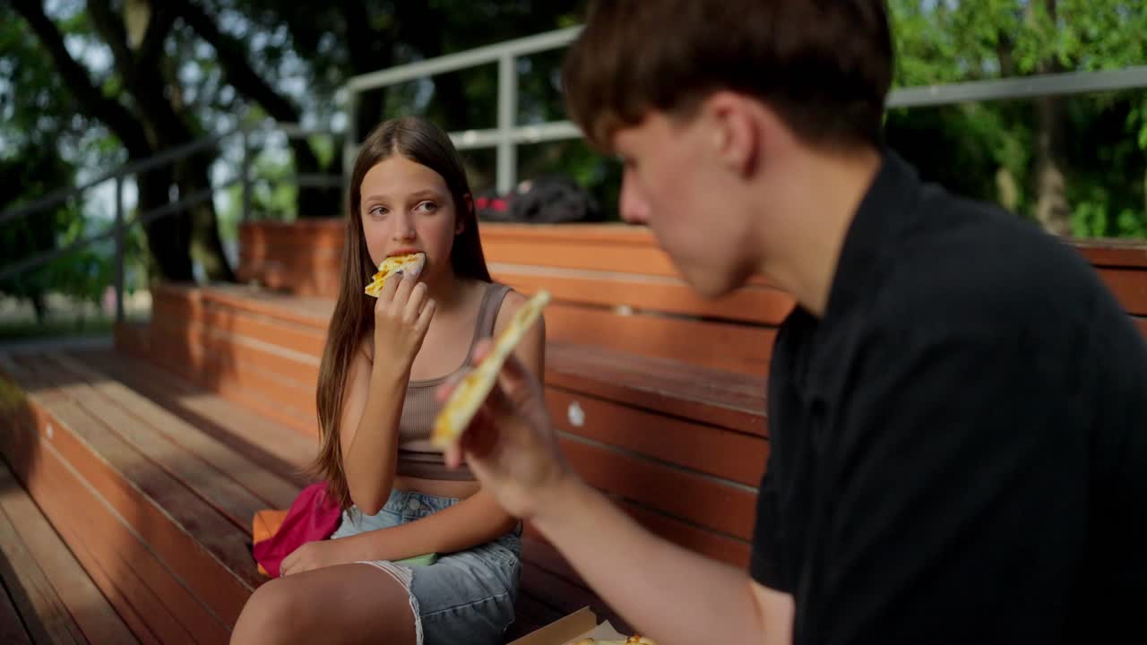 To unge venner nyter en pizzalunsj sammen utendørs.