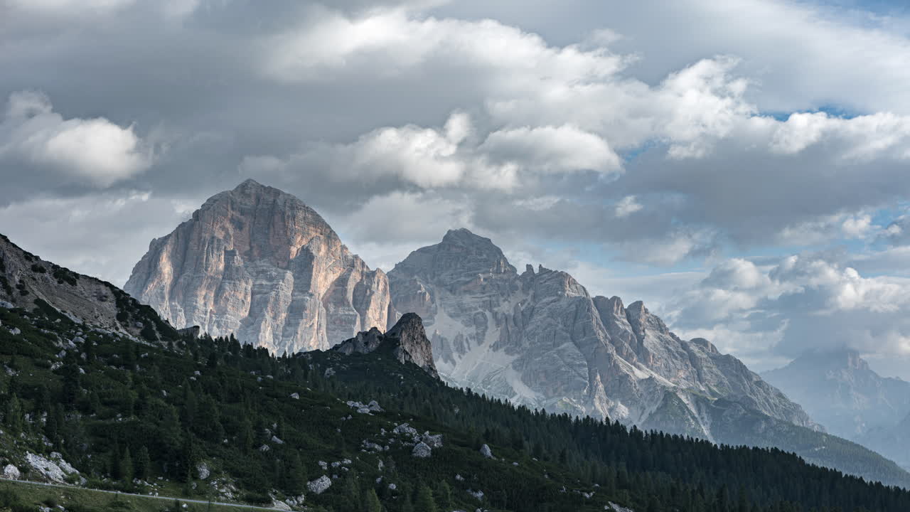 Grey moody clouds flowing above massive Dolomite mountains, time lapse