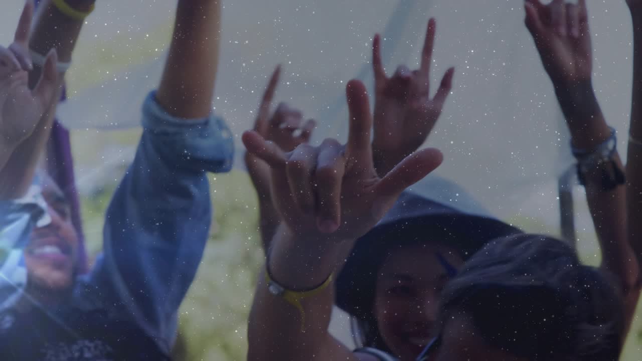 Crowd raising hands at outdoor festival, responding to beat, showing wristbands and purple flag