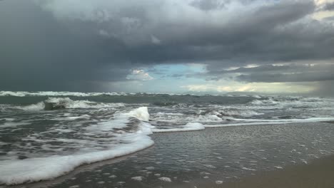 sea waves run over the sandy shore, storm clouds in the background