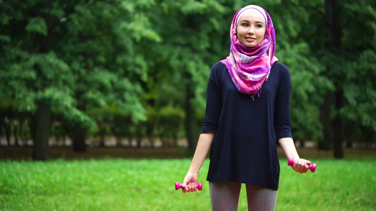 Woman in Hijab Exercising Outdoors with Dumbbells