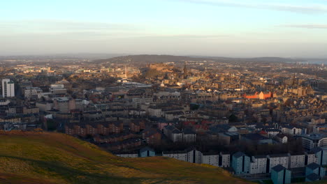 vía dejada sobre los riscos de salisbury en el parque de holyrood con la ciudad de edimburgo debajo cuando amanece, escocia