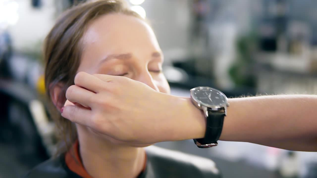 Make up artist gently put on base foundation on a model's face using a sponge. Close up of model's face