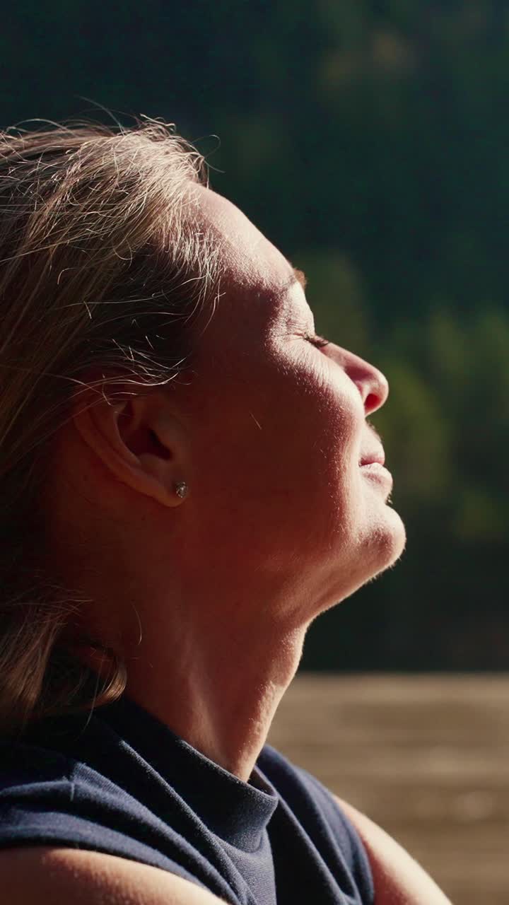La luce soffusa del sole le illumina il viso. Chiude gli occhi, respirando profondamente, con calma. Il sole le accarezza la pelle, delicato e caldo. La sua testa si reclina all'indietro, serena nell'immobilità. La quiete della natura la circonda