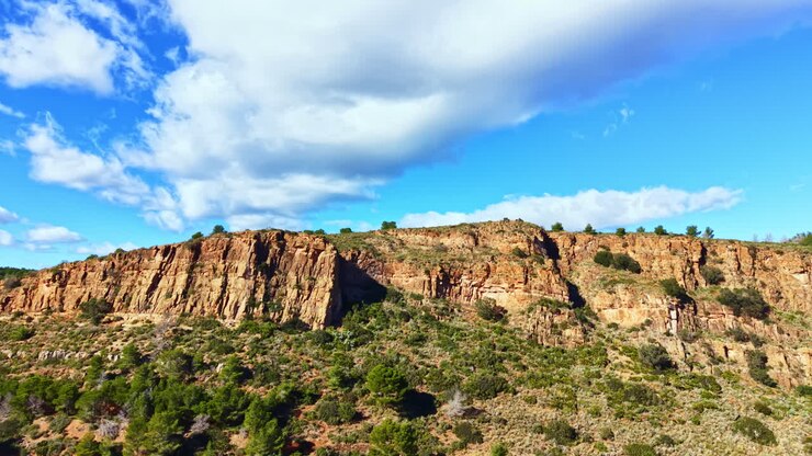 Paesaggio di scogliere rocciose sotto un cielo azzurro con nuvole, visto di giorno in un ambiente naturale.