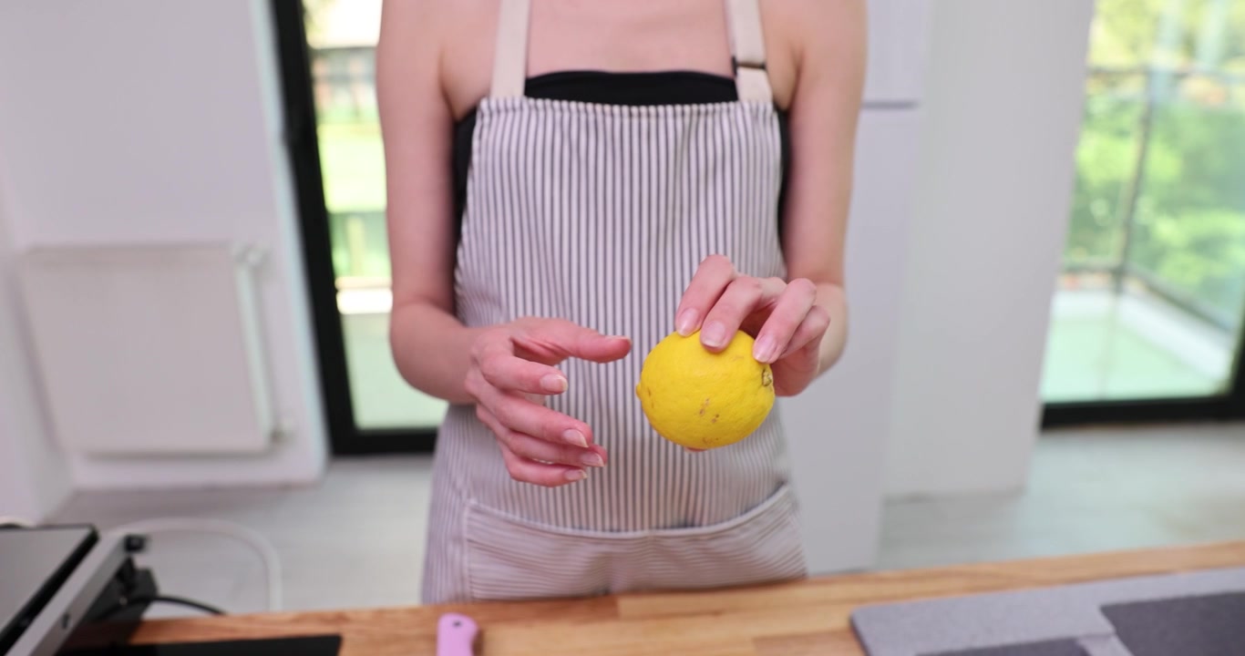Cocinera sostiene un limón antes de usarlo en la cocina durante la preparación de alimentos