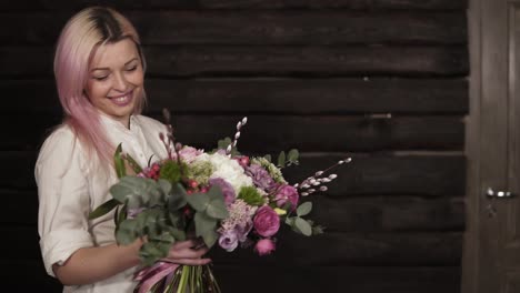 Tender,-beautiful-girl-whirls-with-flowers-in-hands,-enjoying-the-beauty-of-a-bouquet.-Dark-background