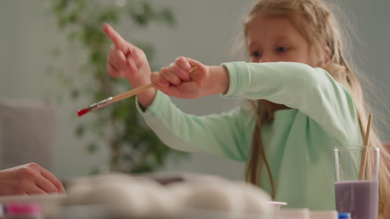 작은 소녀 미술 학생은 적색 페인트를 흘려서 에브루 그림을 만 ⁇ 니다.