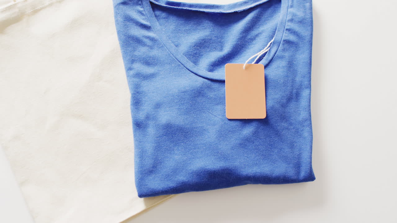 video de primer plano de una camiseta azul plegada con etiqueta en un fondo blanco