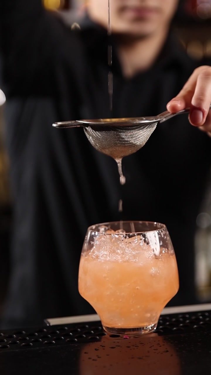 Bartender profissional coando um coquetel refrescante em um copo