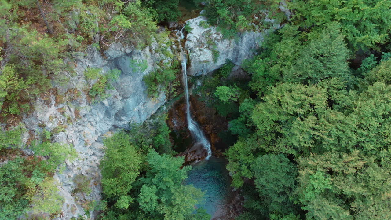 Riprese con drone sopra la Cascata di Roccia Rossa sul Monte Olimpo che mostrano la cascata di 18-20 metri circondata da fitta vegetazione verde all'interno del Canyon di Orlias vicino a Dion, Grecia