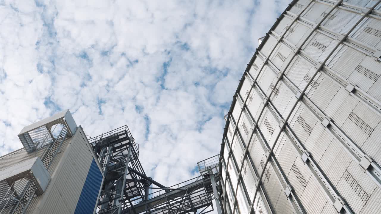 Steel grain elevator. Modern agricultural plant on sky background. Large silver containers for drying grains. Metal construction of a large architecture