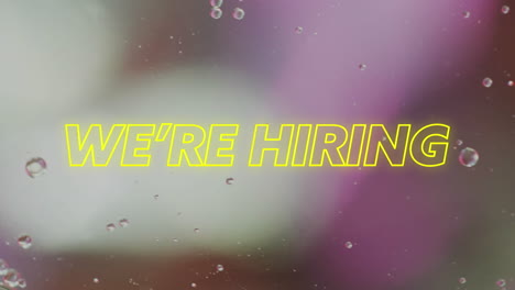 animation of we're hiring text over close up of liquid and baubles