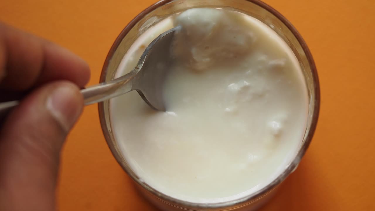 Hand scooping Yogurt from Glass