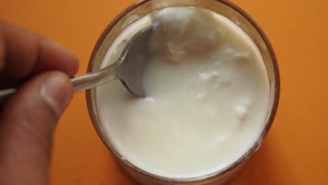 hand scooping yogurt from glass