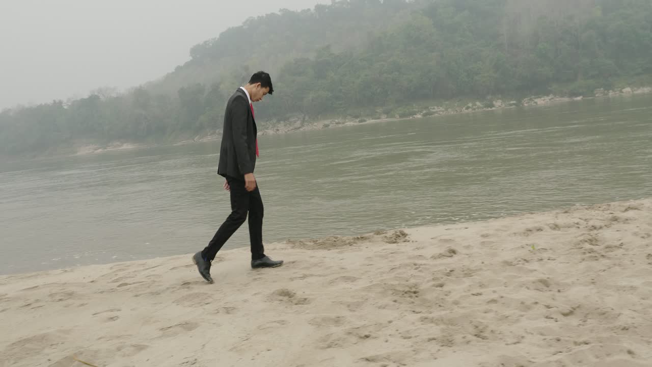 Businessman walking along a riverbank