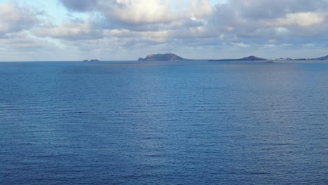 A-static-shot-of-calm-water-of-deep-blue-ocean-with-clouds-and-sun-reflection