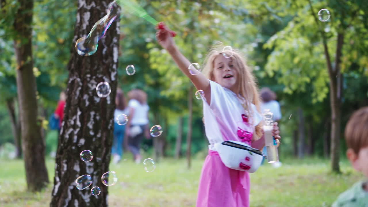 Little girl blowing soap bubbles. Little cute blonde girl blowing bubbles in park