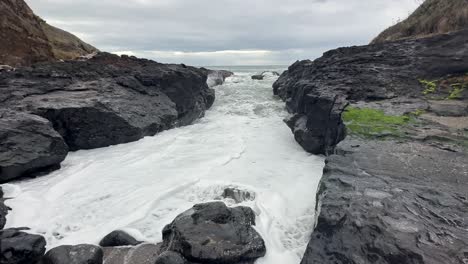 Waves-splash-through-a-rocky-channel-on-the-beach-in-Oregon,-USA