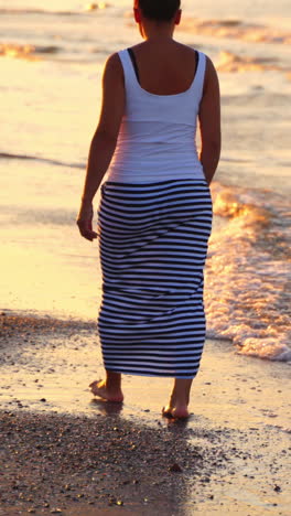 lonely woman walking on beach. back portrait girl walking on sea beach in stylish wear