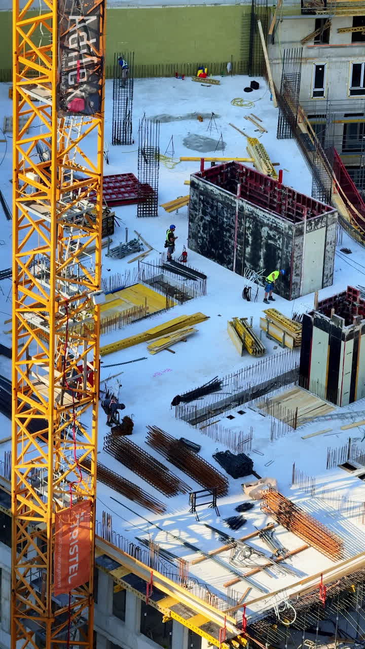Construction site with crane and workers. Workers are engaged in construction activities at a site, surrounded by machinery and building materials during the day