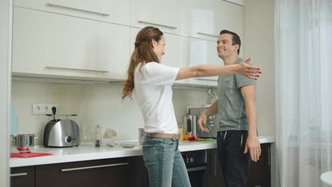 Joyful-couple-hugging-each-other-at-kitchen.-Happy-husband-twisting-smiling-wife