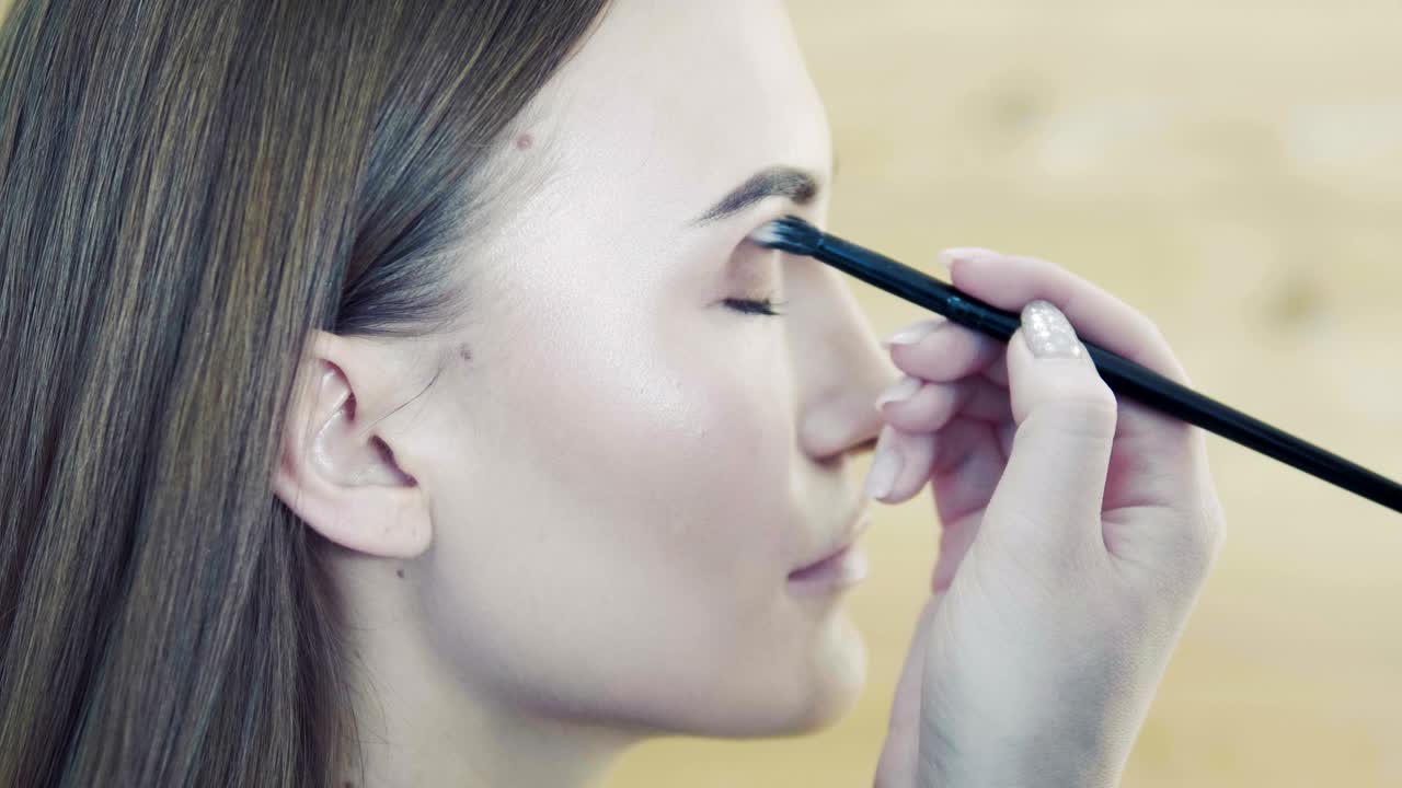 el estilista de maquillaje hace el efecto de los ojos de humo para el modelo en la sesión de fotos