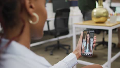 Mujer-De-Negocios-Afroamericana-Usando-Un-Teléfono-Inteligente-Para-Videollamada-Con-Un-Colega-De-Negocios-Caucásico