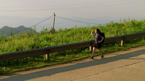 young female backpacker walking alone with his backpack on mountains road in slow motion