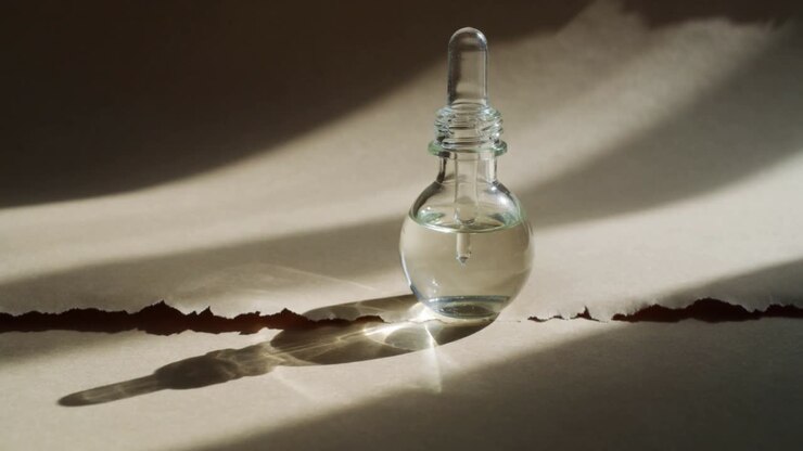 Skiftende lys bader en liten dråpeflaske av glass på revet papir, og skaper bevegelig glimt og skygge.