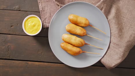 video of corn dogs with dips on a wooden surface