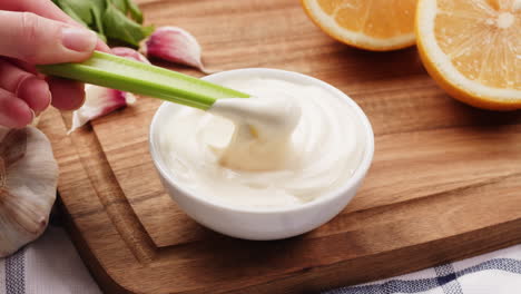 celery dipping into mayonnaise with garlic and lemon