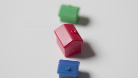 home buying concept with red blue and green plastic models of houses revolving on white background