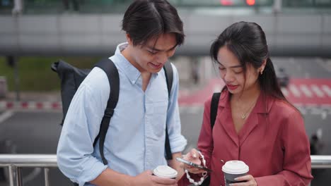 couple looking at a phone while on a city bridge