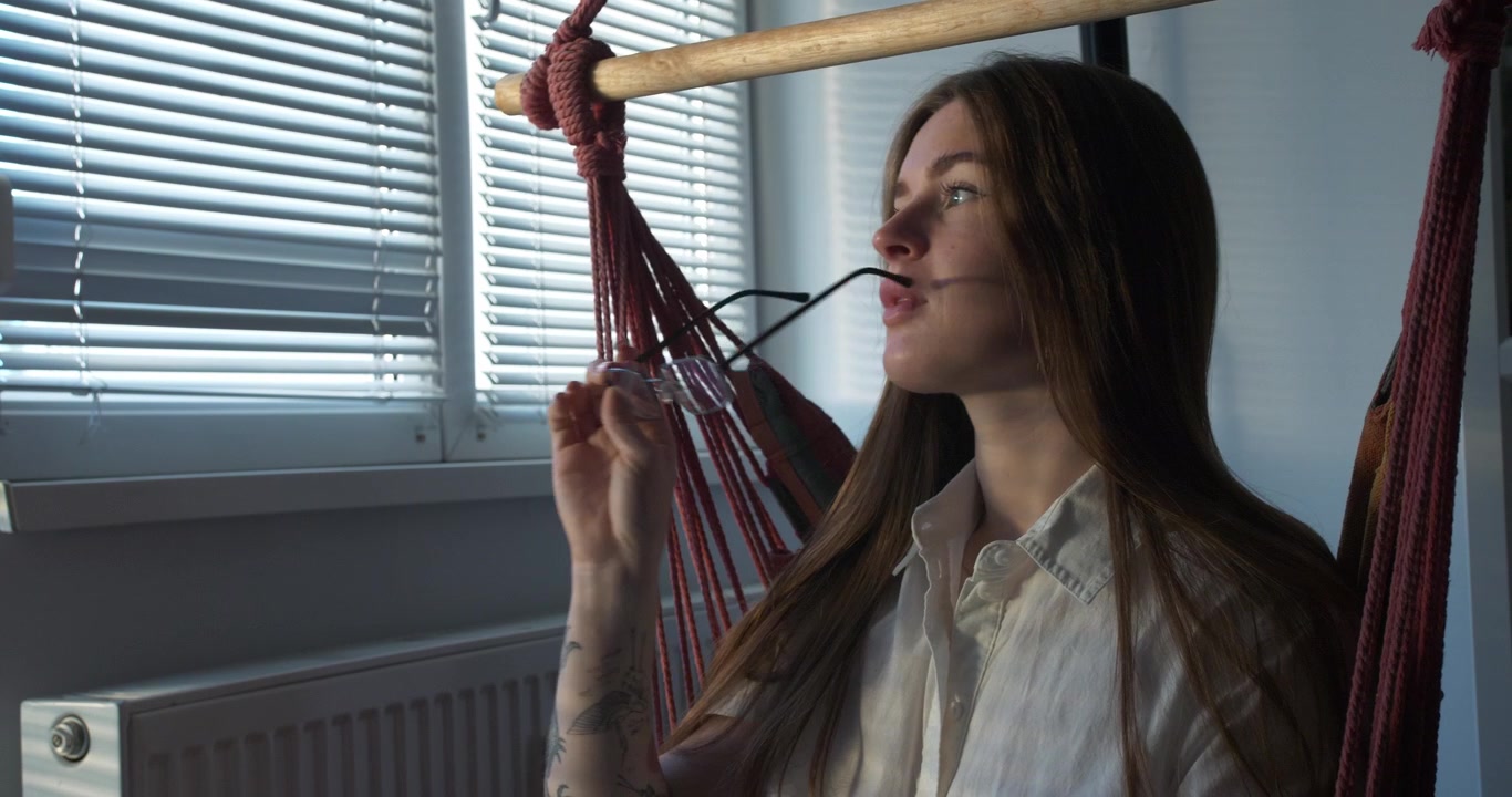 Krásná sexy dívka s brýlemi připravená číst knihu, sedící na houpačce. Polodetail.