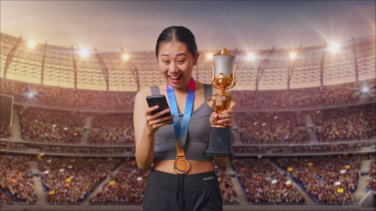 Asian Woman With A Gold Medal And Trophy Looking At Smartphone Then Saying Wow At The Stadium
