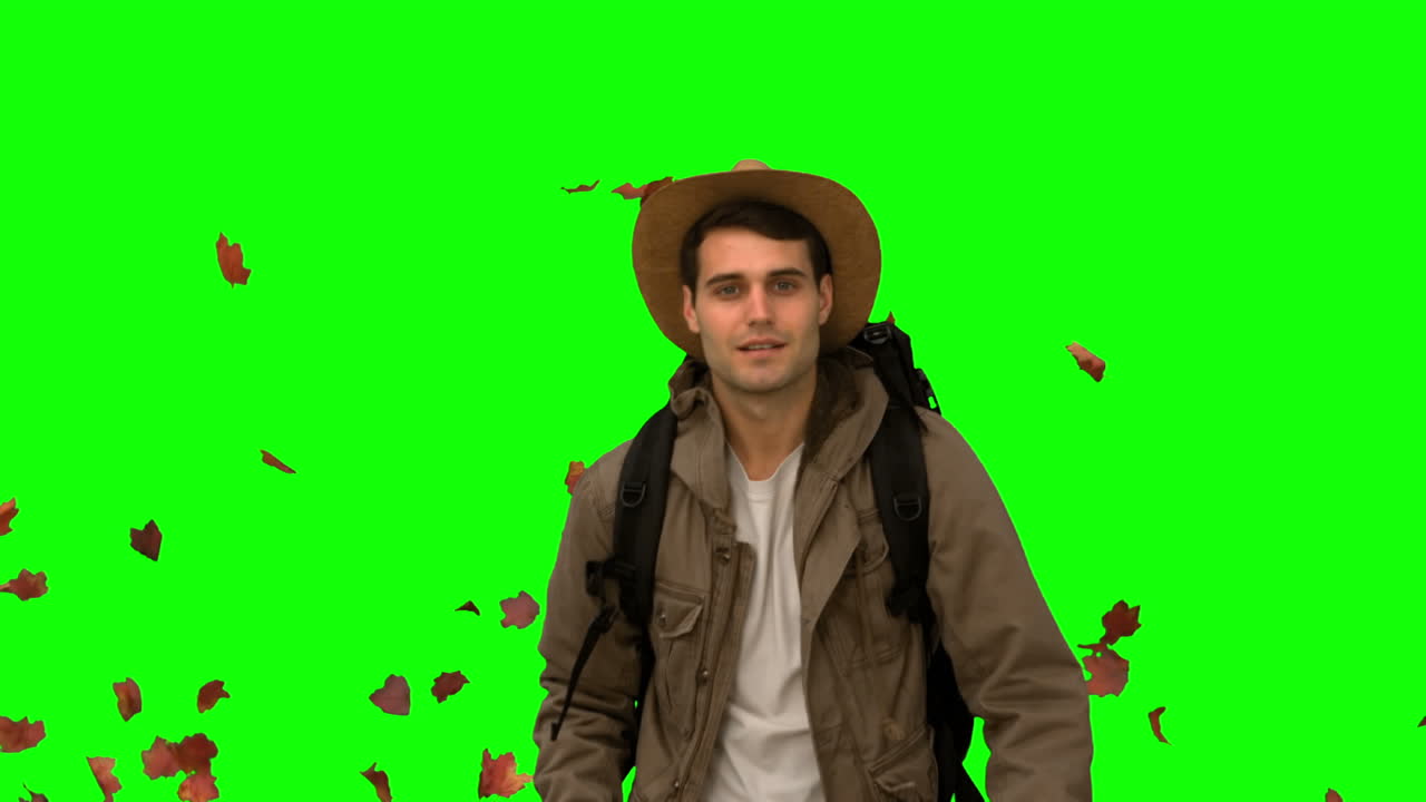 hombre caminando bajo hojas cayendo en la pantalla verde