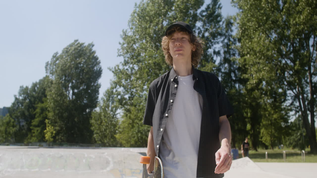 un chico caucásico caminando en el parque de skate.