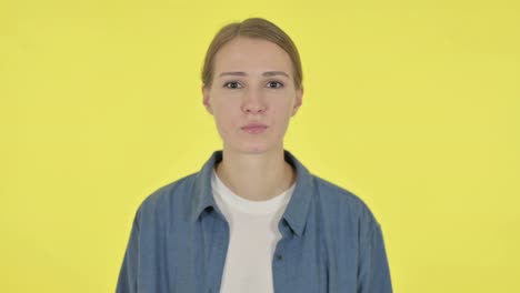 rejecting  woman shaking head in denial on yellow background